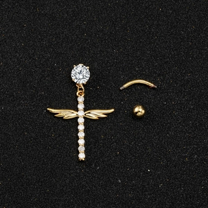 Macro detail of golden belly button ring with angel wings cross and sparkling crystals