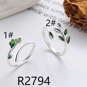Detailed view of silver rings featuring green enamel leaves and nature inspired designs