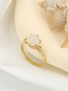 Nahaufnahme eines goldenen Rings mit großem weißem Edelstein und kleinen Diamanten