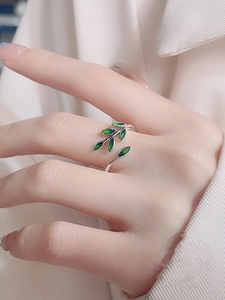 Close-up of adjustable silver leaf ring with green enamel finish on a finger