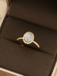Detailansicht eines ovalen Mondsteinrings mit Diamant-Halo und goldener Fassung