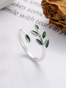 Top view of silver adjustable ring with green enamel leaves on aesthetic background