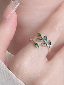 Detailed view of silver adjustable ring featuring green leaf enamel design on a finger