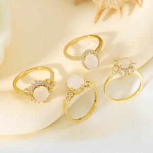Elegantes Goldring-Set mit weißen Steinen und Diamanten auf warmem beigem Grund
