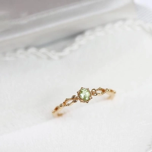 Dettaglio anello dorato traforato con peridoto ovale verde oliva e stile vintage