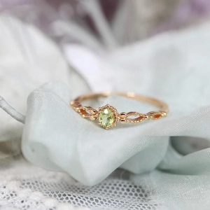 Dettaglio macro dell'anello con peridoto verde ovale e decorazione traforata in oro rosa