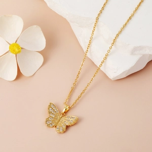 Nahaufnahme der goldenen Schmetterlingskette mit Zirkonia auf rosa Hintergrund