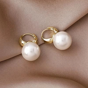 Elegant gold metal hoop earrings with round white pearls on champagne silk fabric