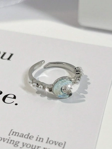 Detalle macro de anillo plateado ajustable con luna azul hielo y perlas blancas