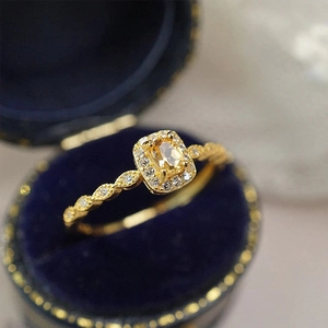 Vista macro de anillo de citrino con halo de diamantes en joyero de terciopelo azul