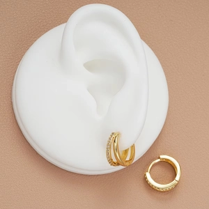Close-up of gold double-hoop earrings featuring sparkling zircons and a polished finish