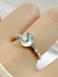 Primer plano de anillo de luna plateado con incrustación irisada y detalles de perlas