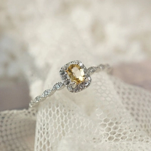 Macro de anillo de citrino amarillo ovalado con halo de diamantes y banda labrada