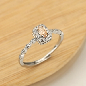 Detalle de anillo con cristal champán ovalado, banda trenzada y circonitas brillantes