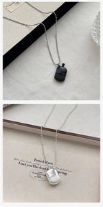 Detail showing mini perfume bottle pendant in black and silver on bead chain