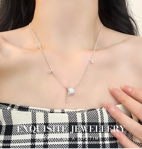 Collier chaîne à billes argentée avec pendentif cylindrique texturé porté par un mannequin