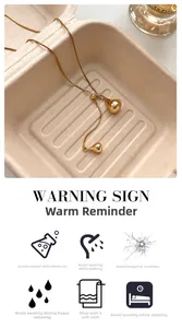 Detail of elegant gold double water drop pendant on thin chain with jewelry care icons