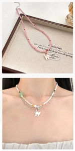 Detailweergave van de roze kralenketting en gelaagde parelketting met kattenhanger