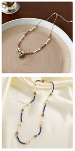 Detail van kralenketting met natuursteen, turquoise, parels en gouden bloemhanger