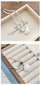 Gros plan sur les pendentifs coquillage et étoile de mer avec perles sur collier de plage