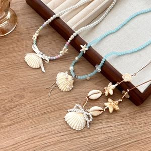 Set de colliers de plage colorés avec coquillages, perles et étoiles de mer sur plateau