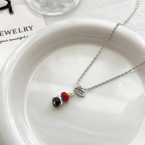 Collar de cuentas minimalista con cuentas de colores y placa Hand Made en un plato