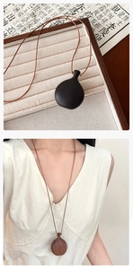 Detailed close-up of ebony and walnut wood flask pendants on a minimalist brown cord necklace