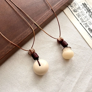 Pendentif style Zen avec perles en résine crème et cordon marron pour un look vintage