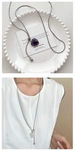 Détail de pendentifs cœur en pierre violette et blanche sur chaînes serpent en argent poli