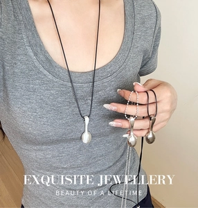 Close-up of spoon-shaped silver pendants with ball chain and black cord necklaces
