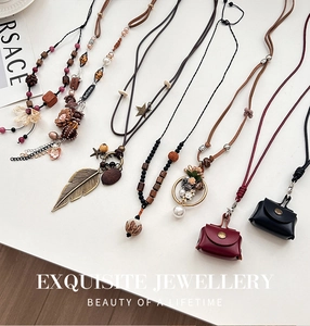 Détail de colliers de style bohème ethnique avec pendentifs plume et fleur sur fond blanc