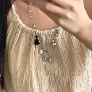 Long collier pendentif chiot avec franges noires et corde tissée pour un look mode chic épuré