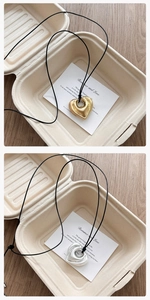 Détail de pendentifs en forme de cœur 3D dorés et argentés avec cordons noirs minimalistes