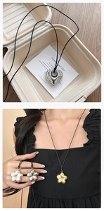 Détail de pendentifs métalliques en forme de cœur et de fleur sur cordons noirs variés
