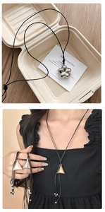 Détail du pendentif triangle géométrique et de la fleur sur un collier en cordelette noire