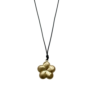 Collier minimaliste fleur dorée mate avec cordon noir élégant sur fond blanc neutre