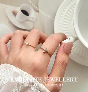 Vista de detalle de dos anillos bañados en oro de 18K con circonitas redondas y marquise