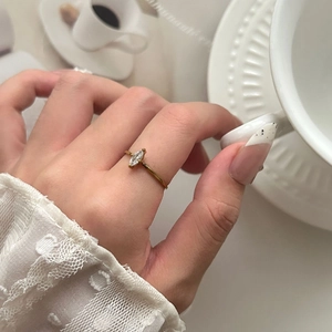 Elegante anillo de titanio bañado en oro de 18K con circón marquesa en mano de mujer