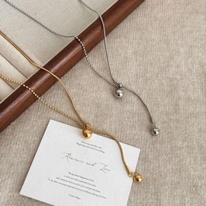 Minimalistische gouden en zilveren bolvormige hanger kettingen op houten juwelendoosje