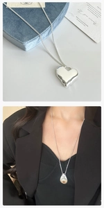 Dettaglio del ciondolo a cuore argento e collana a goccia su abito nero elegante
