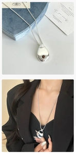 Dettaglio della collana a goccia argento con pietra marrone su blazer e scatola