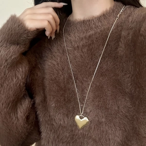 Minimalistische gouden hartjesketting op bruine trui, elegante metalen sieraad voor dames
