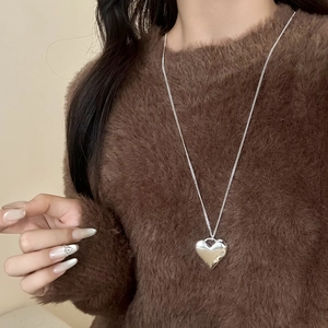 Minimalistische zilveren hart hanger ketting met fijne ketting over bruine trui
