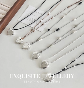 Detailed close-up of various heart-shaped pendant necklaces with irregular texture on white background