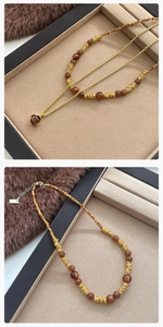Detailopname van tijgeroogkralen en gouden ketting aan een vintage truihalsketting