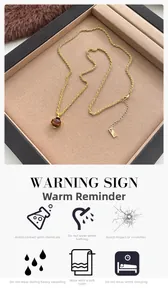Detail van tijgeroog hanger aan gouden koordketting met vintage sieradendoosje display