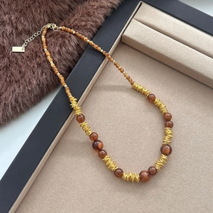 Vintage tijgeroog kralenketting met gouden metalen accenten op beige display