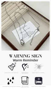 Polished silver teardrop pendant on box chain displayed in a wooden jewelry tray