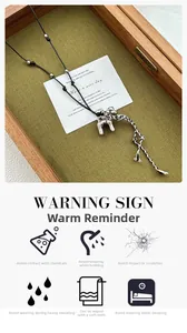 Silver dog pendant necklace featuring black rope and tassel displayed on wooden tray