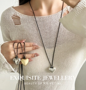 Elegante zilveren hartvormige hanger aan zwart koord gedragen door model voor stijlvolle ketting